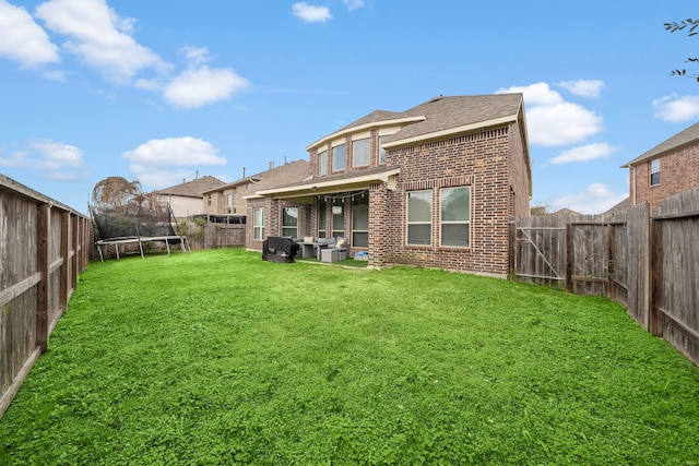 3627 Grand Promenade Ln, Stafford, TX 77477 - rear view of property featuring a trampoline, brick siding, and a shingled roof