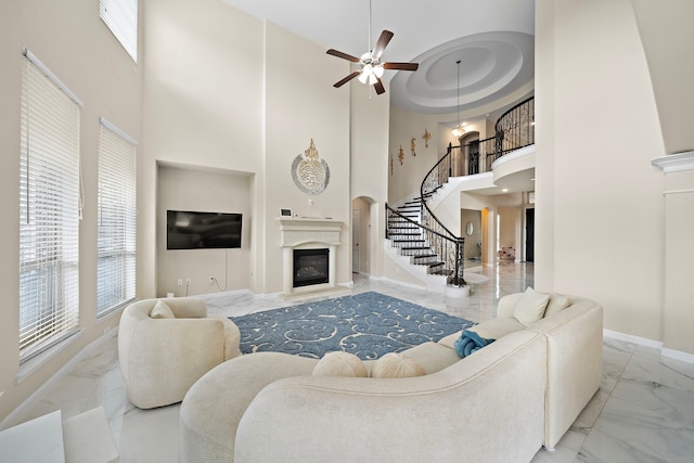 3627 Grand Promenade Ln, Stafford, TX 77477 - living area with marble look tile flooring, a glass covered fireplace, a towering ceiling, healthy amount of natural light, and stairs