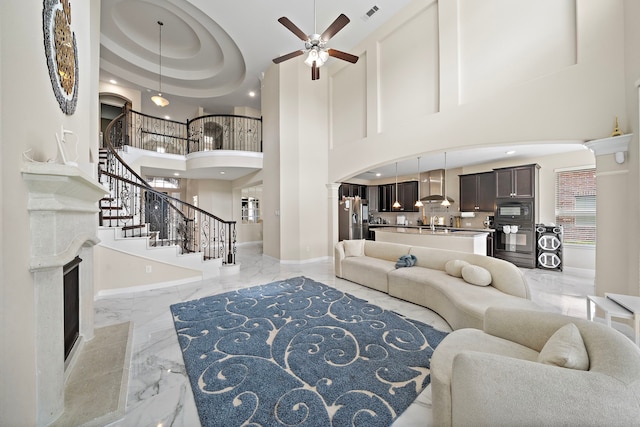 3627 Grand Promenade Ln, Stafford, TX 77477 - living area with light marble finish floors, a towering ceiling, a ceiling fan, decorative columns, and stairway