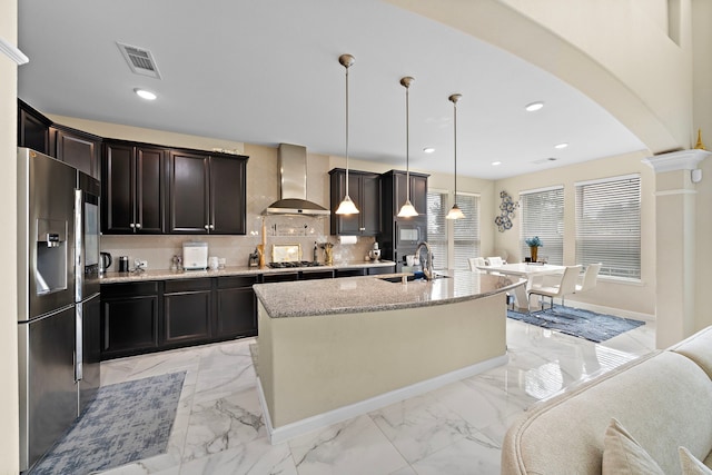 3627 Grand Promenade Ln, Stafford, TX 77477 - kitchen with stainless steel fridge with ice dispenser, wall chimney range hood, light marble finish floors, a sink, and arched walkways