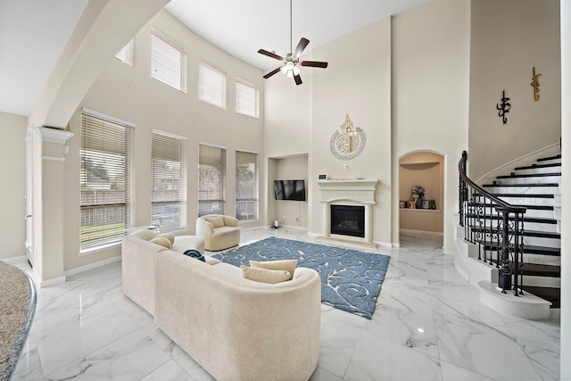 3627 Grand Promenade Ln, Stafford, TX 77477 - living room with marble tiled flooring, a ceiling fan, a glass covered fireplace, built in features, and a high ceiling