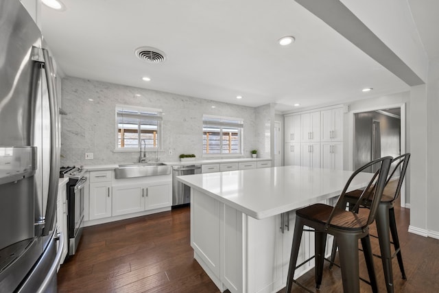 3531 Westridge St, Houston, TX 77025 - kitchen featuring stainless steel appliances, a sink, dark wood-style flooring, a kitchen island, and a kitchen bar