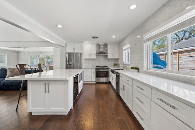 3531 Westridge St, Houston, TX 77025 - kitchen featuring stainless steel appliances, wall chimney exhaust hood, a breakfast bar, a sink, and plenty of natural light
