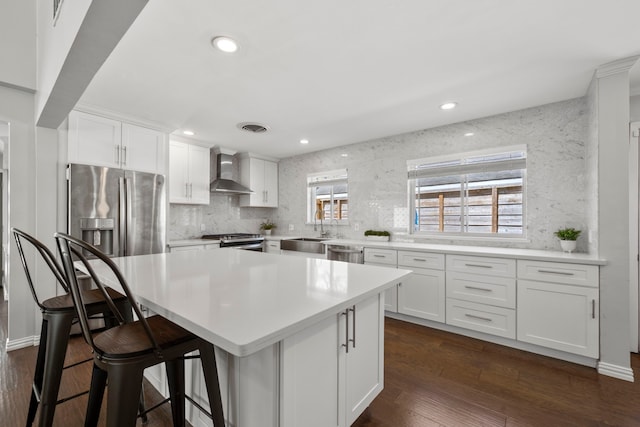 3531 Westridge St, Houston, TX 77025 - kitchen with wall chimney exhaust hood, appliances with stainless steel finishes, a sink, white cabinetry, and recessed lighting