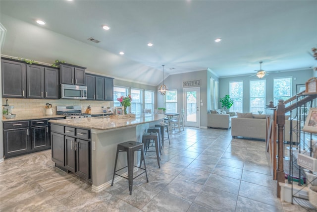 2255 Golden Laurel Dr, Conroe, TX 77304 - kitchen with stainless steel appliances, ornamental molding, backsplash, a breakfast bar, and an island with sink