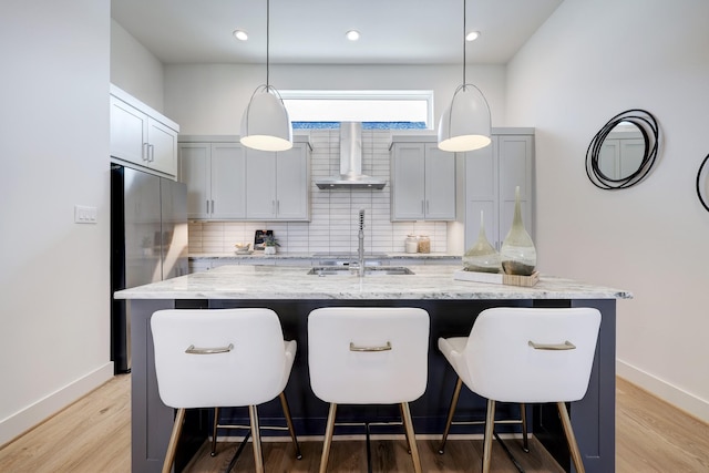 2105 Emancipation Ave, Houston, TX 77003 - kitchen featuring wall chimney exhaust hood, freestanding refrigerator, tasteful backsplash, a kitchen island with sink, and a kitchen bar