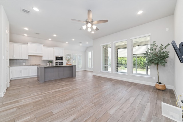 kitchen featuring stainless steel appliances, white cabinetry, tasteful backsplash, ceiling fan, and light wood finished floors