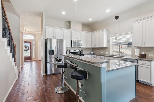 14039 Pawnee Bend Dr, Cypress, TX 77429 - kitchen featuring stainless steel appliances, a sink, a kitchen island, white cabinetry, and light stone counters