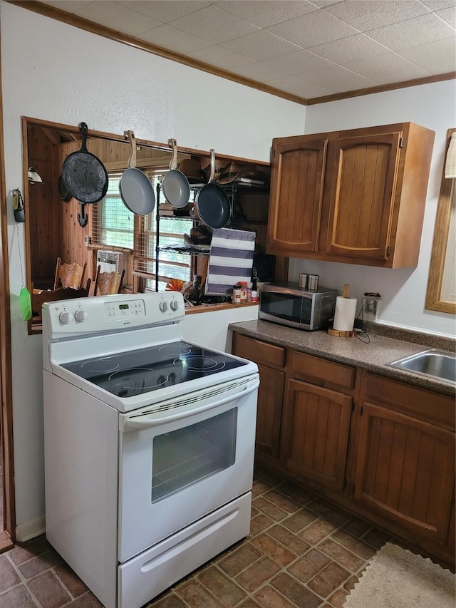 20 Shannon St, Huntsville, TX 77320 - kitchen featuring white range with electric cooktop, stainless steel microwave, brown cabinets, ornamental molding, and a sink