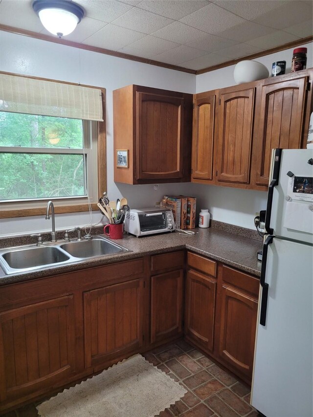 20 Shannon St, Huntsville, TX 77320 - kitchen with freestanding refrigerator, a sink, dark countertops, brown cabinetry, and dark stone finish flooring