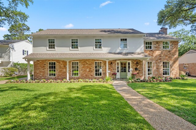 13826 Pinerock Ln, Houston, TX 77079 - view of front facade with a chimney, a front yard, and brick siding