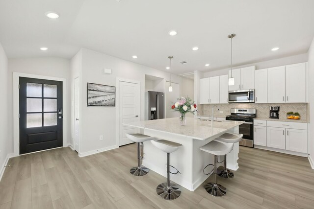 kitchen featuring appliances with stainless steel finishes, light wood finished floors, decorative backsplash, a breakfast bar, and recessed lighting
