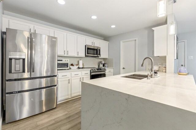 8051 Bay Branch Dr Unit 324, The Woodlands, TX 77382 - kitchen with appliances with stainless steel finishes, a sink, white cabinets, recessed lighting, and a peninsula