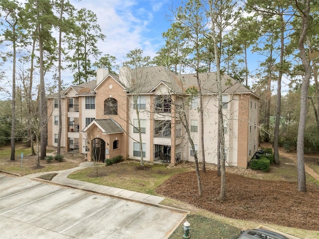 8051 Bay Branch Dr Unit 324, The Woodlands, TX 77382 - view of property featuring brick siding, a shingled roof, and uncovered parking
