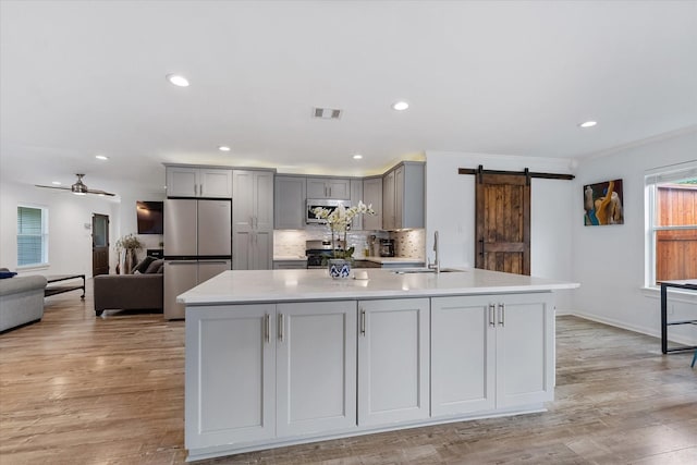 3003 Randall St, Houston, TX 77018 - kitchen with a sink, stainless steel appliances, gray cabinetry, a barn door, and light countertops