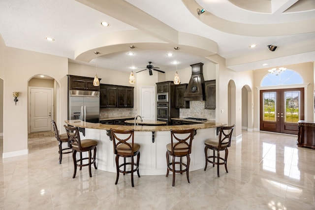 2119 Red Bird Ln, Brookshire, TX 77423 - kitchen featuring arched walkways, built in appliances, custom exhaust hood, tasteful backsplash, and recessed lighting