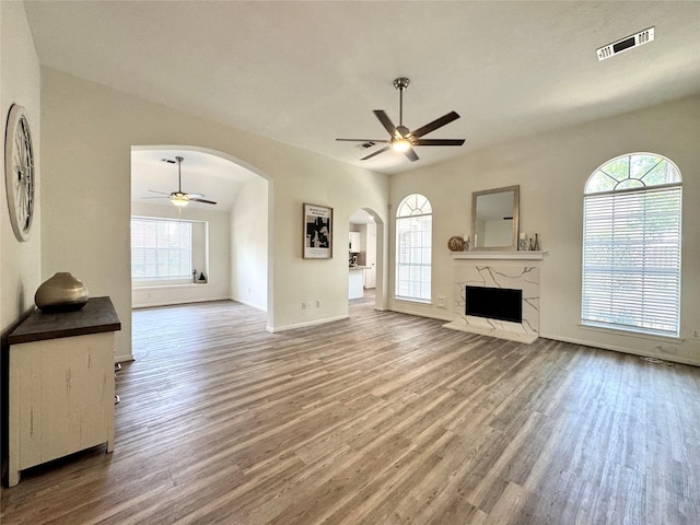 9630 E Withers Way Cir, Houston, TX 77065 - unfurnished living room featuring a ceiling fan, arched walkways, healthy amount of natural light, and wood finished floors
