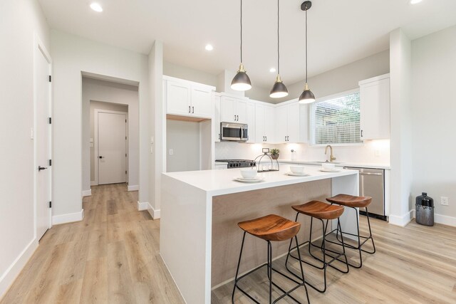 3312 Bremond St, Houston, TX 77004 - kitchen featuring appliances with stainless steel finishes, a sink, light wood-style floors, white cabinetry, and light countertops