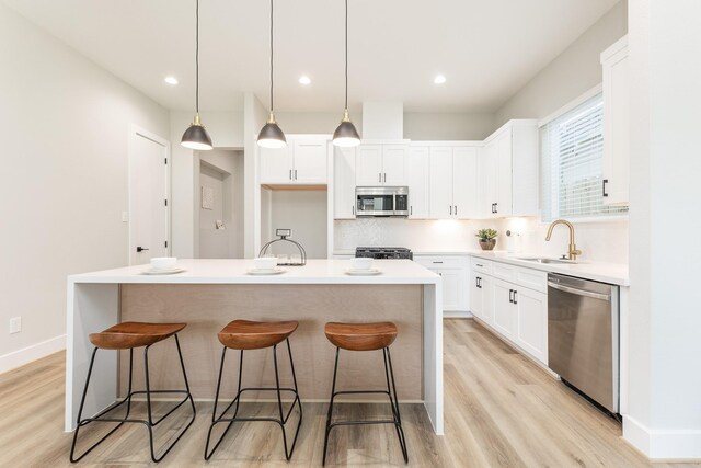 3312 Bremond St, Houston, TX 77004 - kitchen with appliances with stainless steel finishes, a sink, light wood finished floors, white cabinetry, and recessed lighting