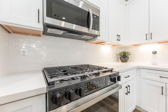 3312 Bremond St, Houston, TX 77004 - kitchen with stainless steel microwave, gas range oven, light countertops, white cabinetry, and decorative backsplash