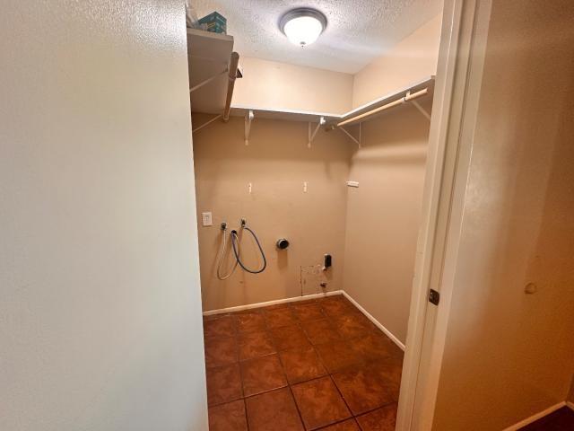 959 Reseda Dr, Houston, TX 77062 - laundry room featuring hookup for a washing machine, hookup for a gas dryer, a textured ceiling, dark tile patterned flooring, and baseboards