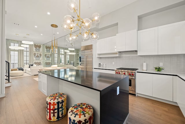 5820 Winsome Ln Unit B, Houston, TX 77057 - kitchen featuring high end appliances, dark countertops, white cabinets, tasteful backsplash, and light wood finished floors