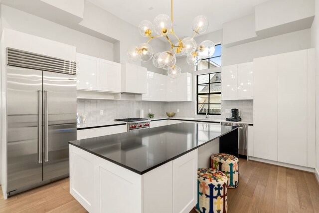 5820 Winsome Ln Unit B, Houston, TX 77057 - kitchen featuring stainless steel appliances, a sink, white cabinetry, decorative backsplash, and light wood-style flooring