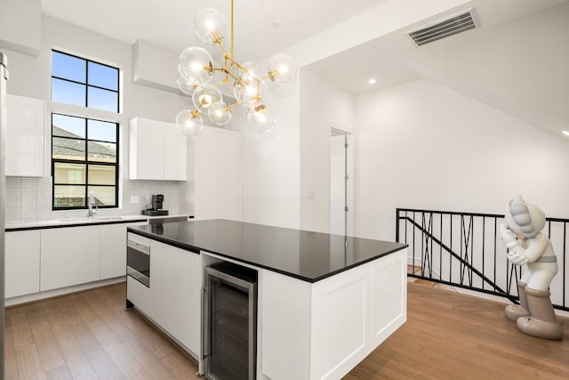 5820 Winsome Ln Unit B, Houston, TX 77057 - kitchen featuring wine cooler, light wood-style floors, a center island, dark countertops, and decorative backsplash