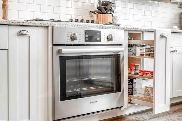 2110 Mason St, Houston, TX 77006 - kitchen view of stainless steel oven, tasteful backsplash, and light stone countertops