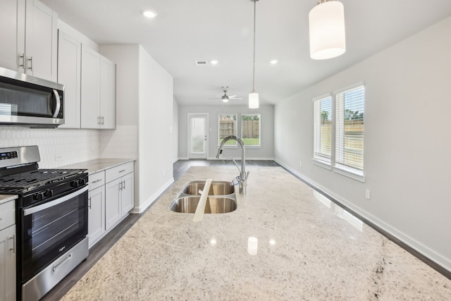 18717 Bliss Pl, New Caney, TX 77357 - kitchen featuring stainless steel appliances, a sink, decorative backsplash, light stone counters, and baseboards