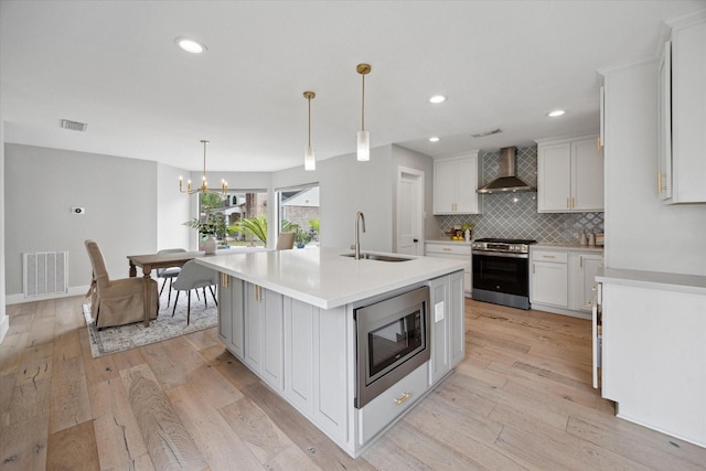 625 Rancho Bauer Dr, Houston, TX 77079 - kitchen with a sink, wall chimney range hood, stainless steel appliances, light wood-style floors, and light countertops