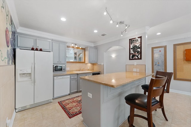 37922 Clubhouse Ln, Magnolia, TX 77355 - kitchen featuring white appliances, gray cabinetry, ornamental molding, a breakfast bar area, and arched walkways