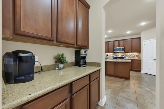 6 Muthill Cir, Conroe, TX 77304 - kitchen featuring appliances with stainless steel finishes, recessed lighting, decorative backsplash, light tile patterned floors, and light stone countertops