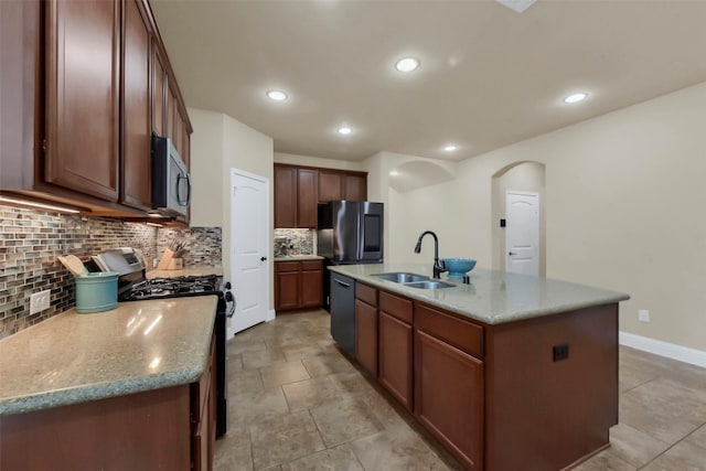 6 Muthill Cir, Conroe, TX 77304 - kitchen with appliances with stainless steel finishes, a sink, decorative backsplash, a center island with sink, and arched walkways