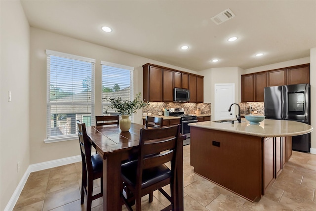 6 Muthill Cir, Conroe, TX 77304 - kitchen with stainless steel appliances, a sink, backsplash, light countertops, and a kitchen island with sink