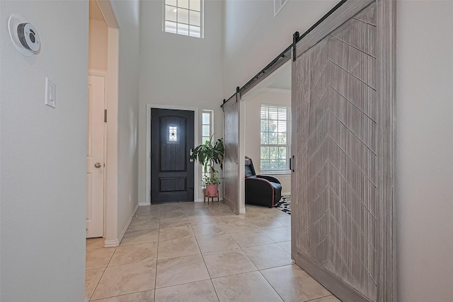 2822 Bluesage Bluff Dr, Richmond, TX 77406 - foyer entrance featuring a barn door, a towering ceiling, baseboards, light tile patterned flooring, and arched walkways