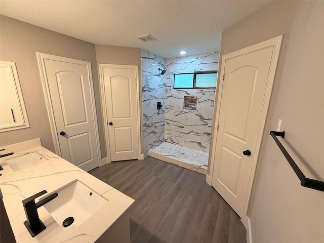 23711 Saxon Way, Hockley, TX 77447 - bathroom featuring a marble finish shower, double vanity, wood finished floors, and a textured ceiling