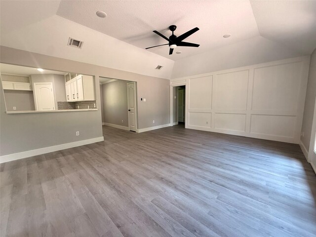 23711 Saxon Way, Hockley, TX 77447 - unfurnished living room featuring a ceiling fan, vaulted ceiling, wood finished floors, baseboards, and a textured ceiling