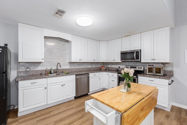 240 7th St, Trinity, TX 75862 - kitchen with appliances with stainless steel finishes, a sink, light wood-type flooring, and backsplash