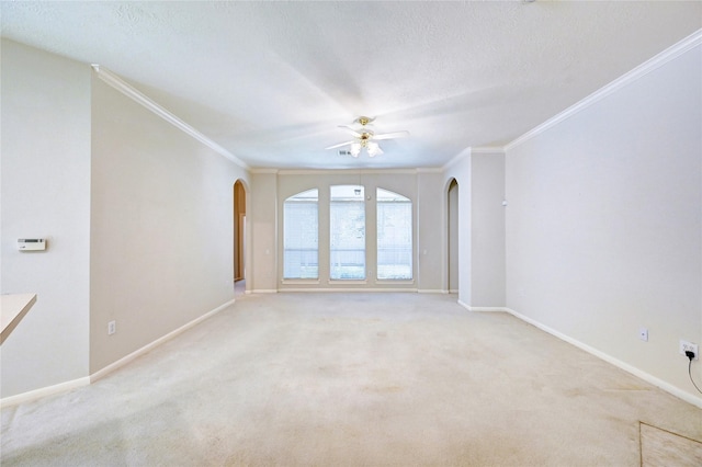 empty room with arched walkways, crown molding, baseboards, light carpet, and ceiling fan