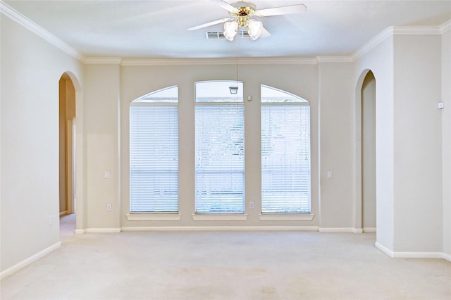 unfurnished room featuring light carpet, arched walkways, ceiling fan, crown molding, and baseboards