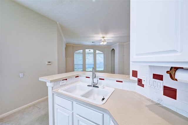 kitchen with a sink, light colored carpet, light countertops, and white cabinetry