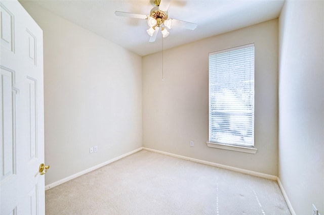 empty room featuring light colored carpet, baseboards, and a ceiling fan