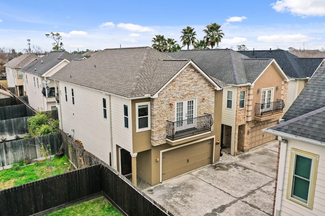 4609 Sharman St, Houston, TX 77009 - rear view of house with a balcony, french doors, stone siding, an attached garage, and concrete driveway
