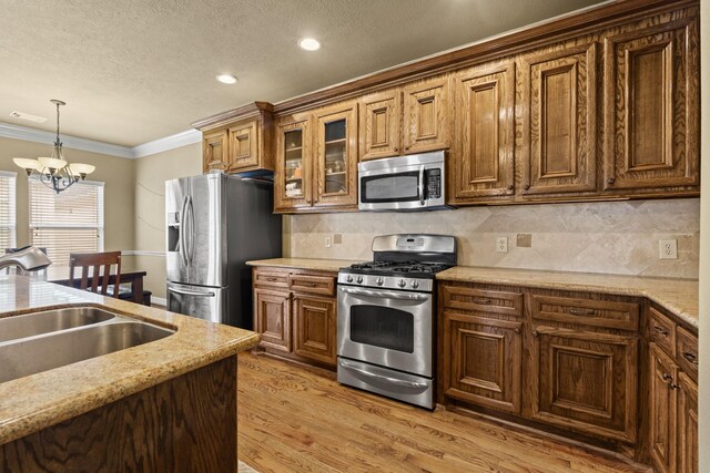 4609 Sharman St, Houston, TX 77009 - kitchen with stainless steel appliances, a sink, hanging light fixtures, light wood-style flooring, and a chandelier