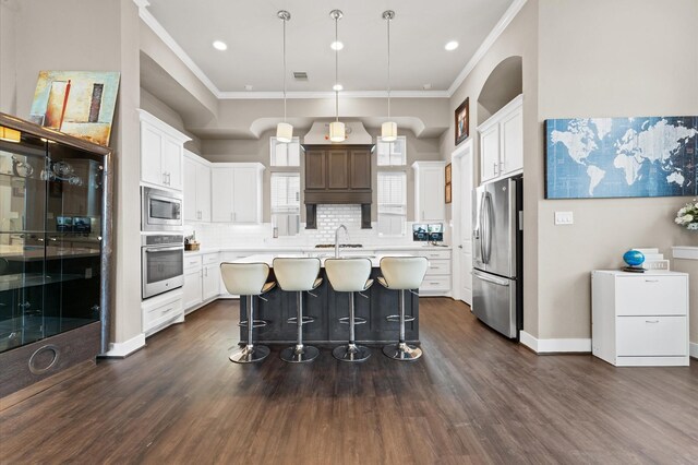 2725 Kennedy St, Houston, TX 77003 - kitchen with appliances with stainless steel finishes, crown molding, light countertops, dark wood-style flooring, and a kitchen bar