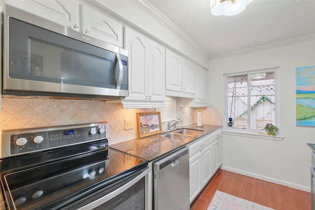 6475 Burgoyne Rd Unit 38, Houston, TX 77057 - kitchen with stainless steel appliances, white cabinets, a sink, decorative backsplash, and crown molding