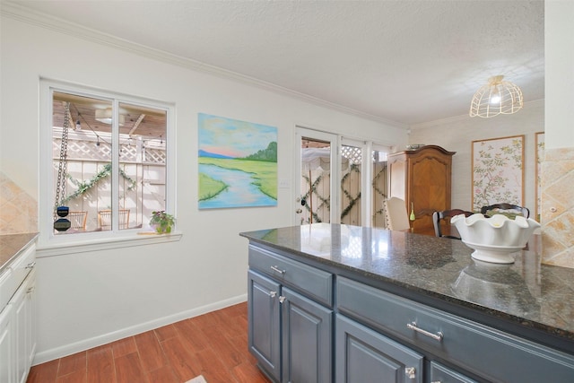 6475 Burgoyne Rd Unit 38, Houston, TX 77057 - kitchen featuring wood finished floors, baseboards, ornamental molding, dark stone countertops, and blue cabinetry