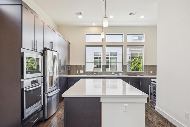1704 Alamo St Unit A, Houston, TX 77007 - kitchen featuring stainless steel appliances, a sink, light countertops, a center island, and decorative backsplash