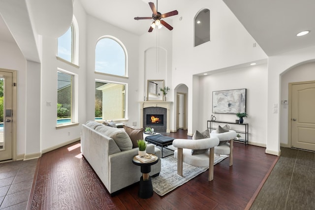 4603 Red Hawk Ct, Sugar Land, TX 77479 - living area featuring a ceiling fan, a tiled fireplace, wood finished floors, a towering ceiling, and baseboards